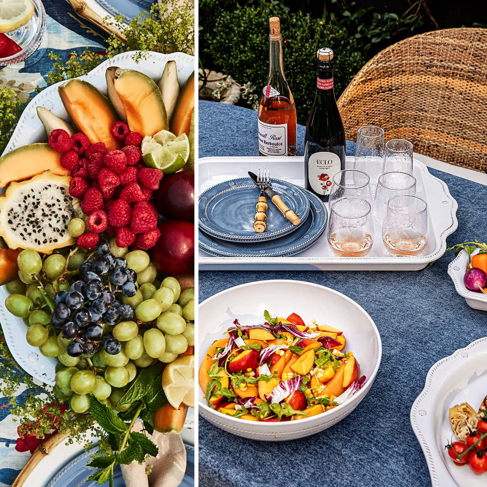 Fruit platter, wine bottles, and salad on a table outdoors.