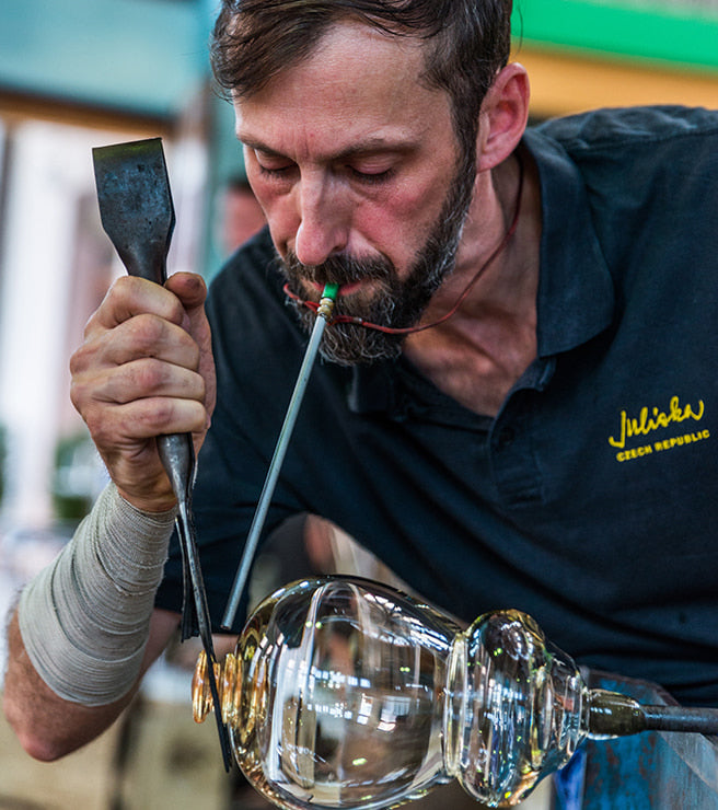 Glassblower shaping molten glass in a workshop setting