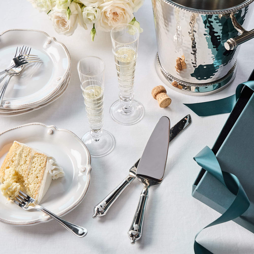 Table setting with cake, champagne glasses, and silverware on a white tablecloth.