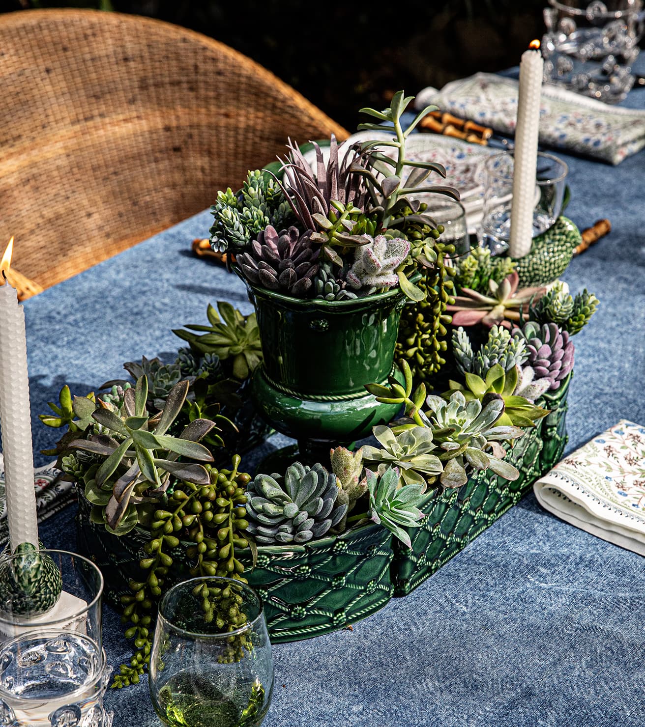 Decorative centerpiece with succulents on a table with candles and glasses.
