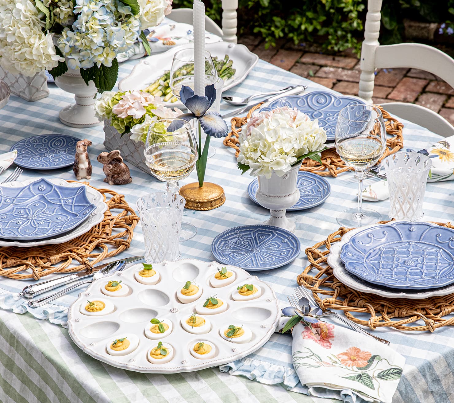 Outdoor table setting with blue ceramic plates, white flowers, and deviled eggs.