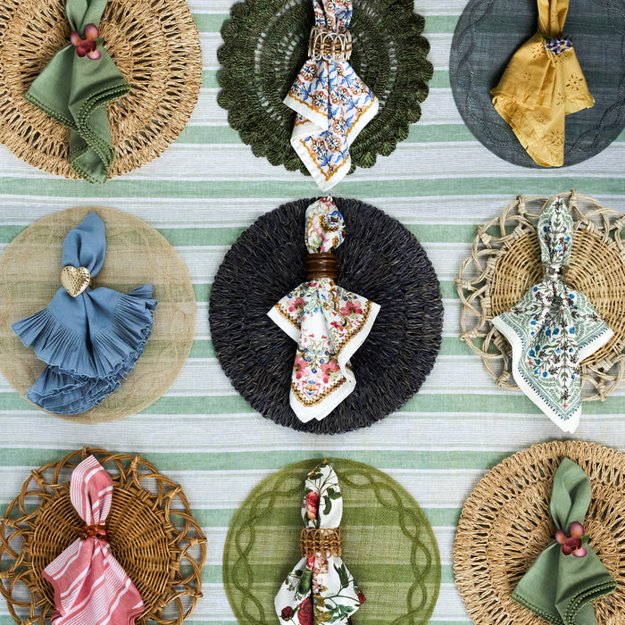 Juliska placemat, napkins, and napkin rings lined up in rows on a tablecloth