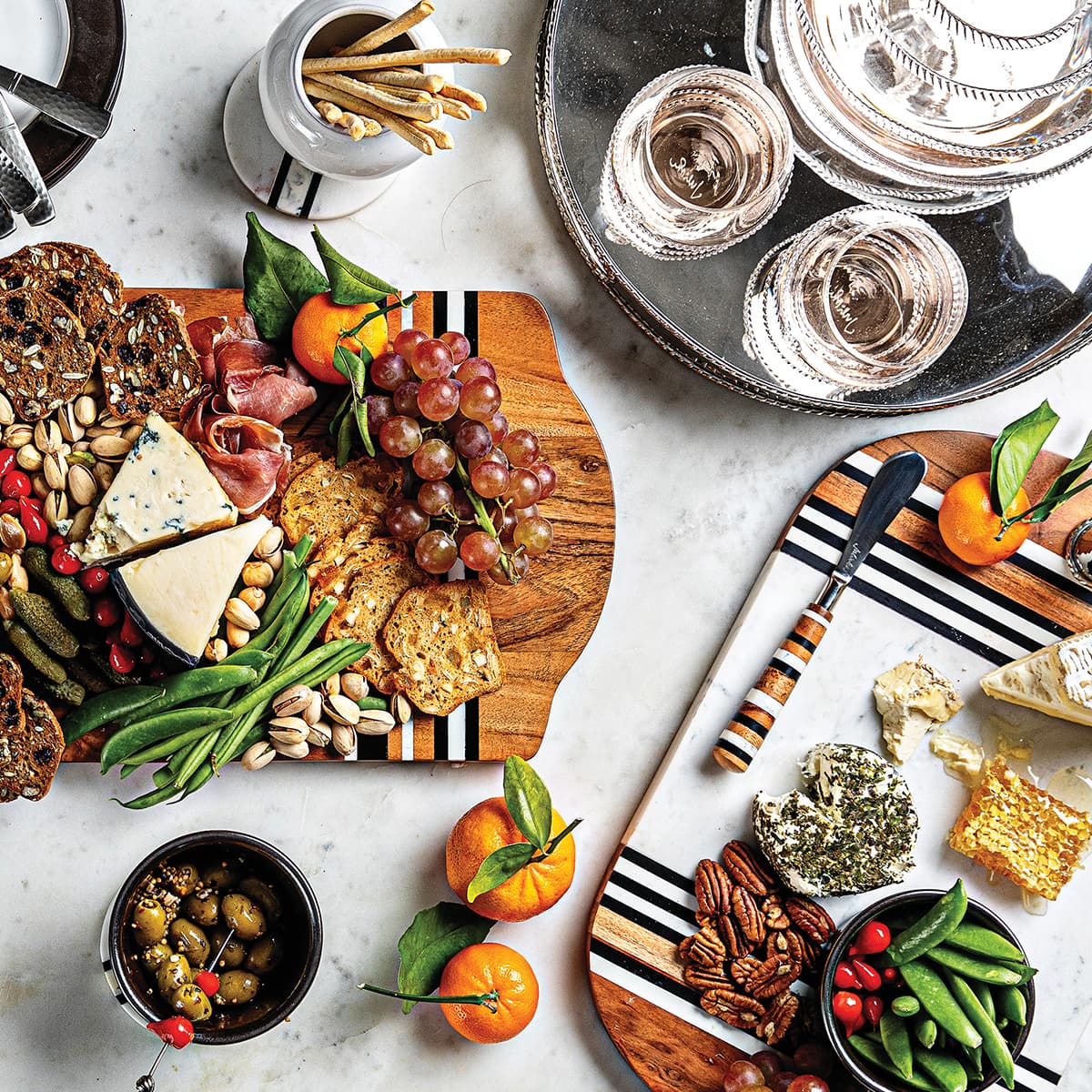 Two stonewood stripe charcuterie boards and a graham metal serving tray displaying beverages