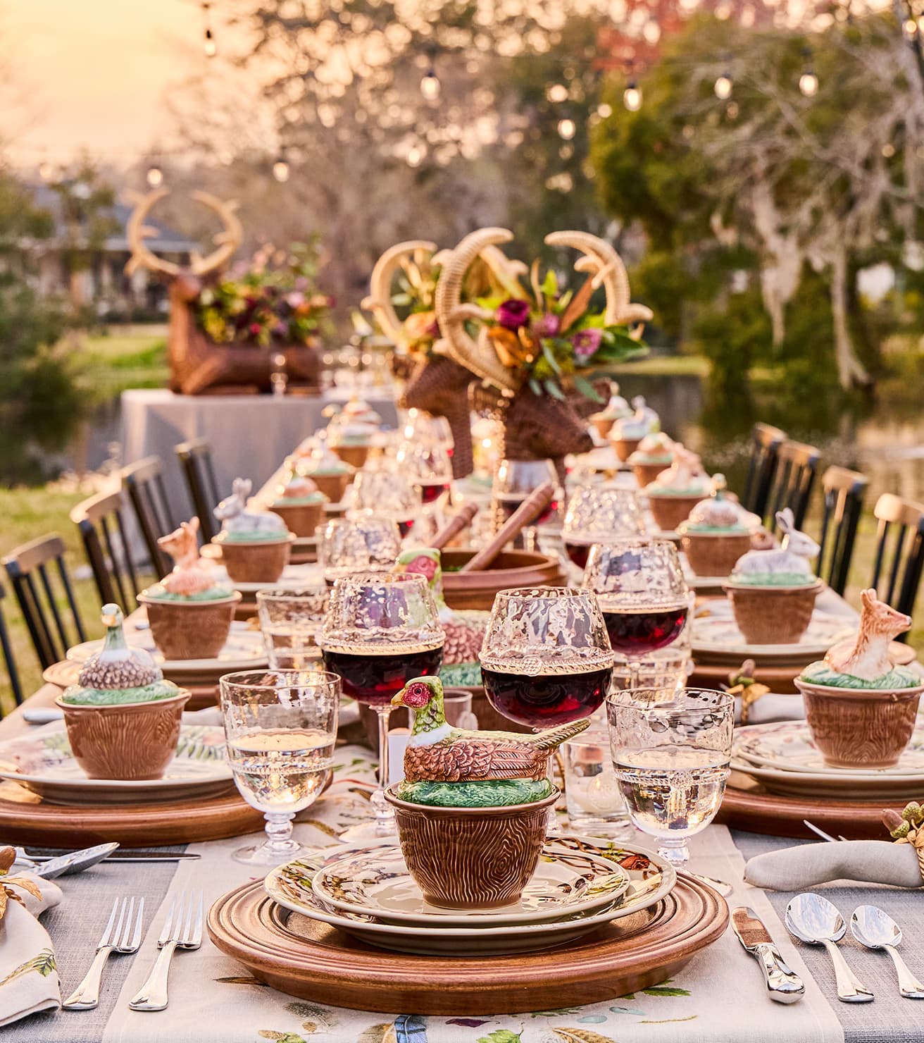 Decorative outdoor table setting with antlers, flowers, and various items on a natural background.