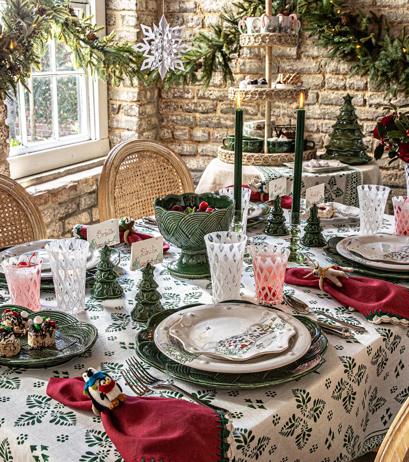 Decorative Christmas table setting with greenery, candles, and festive tableware.