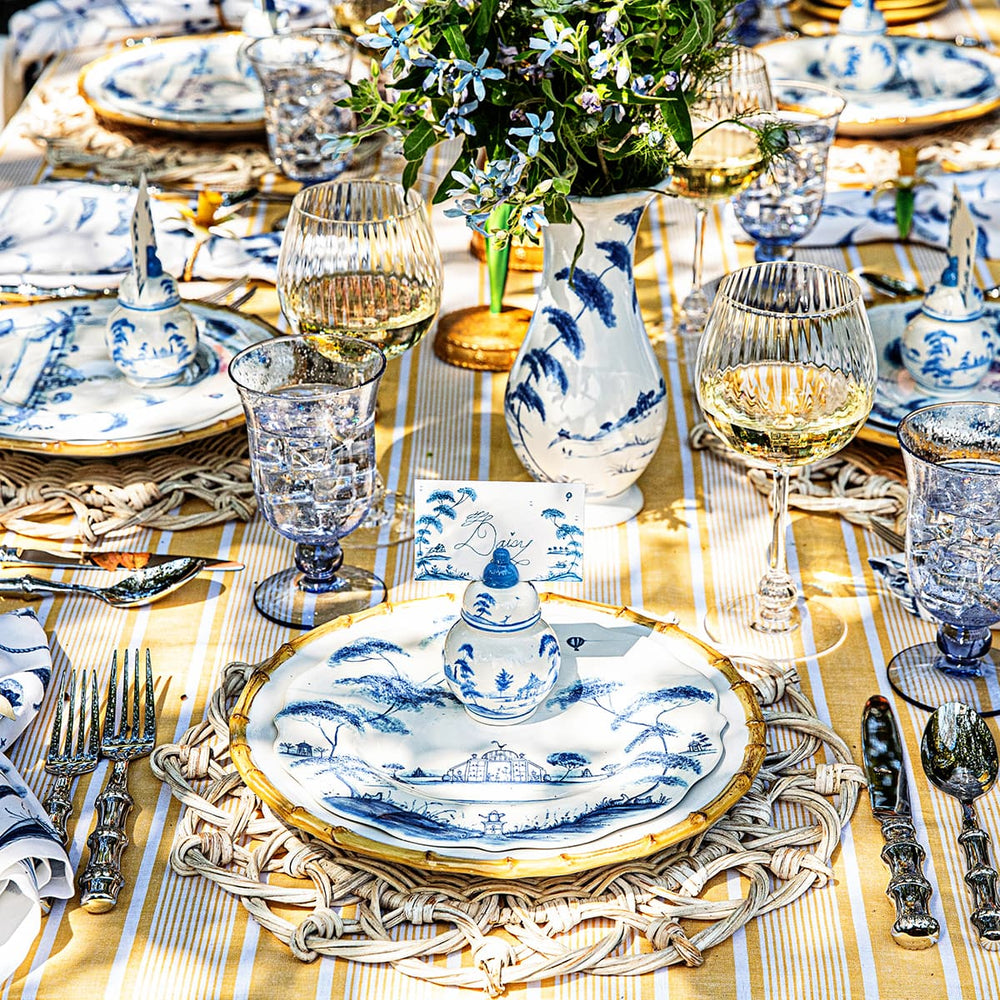 Image showing outdoor tablescape with bamboo and country estate delft blue plates on top of a yellow tablecloth.