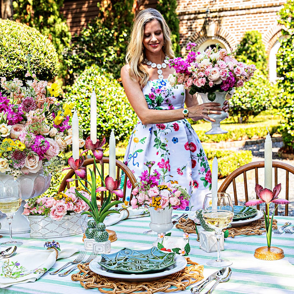 Woman holding bouquet of flowers standing next to an al fresco table set for a luncheon