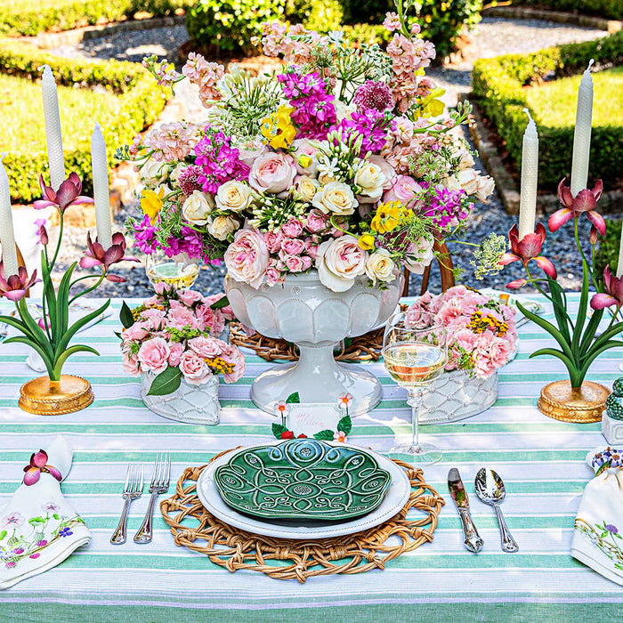 Tablescape with large floral decorations in the center amongst jardin du monde plates, meadow walk candelabras and linens