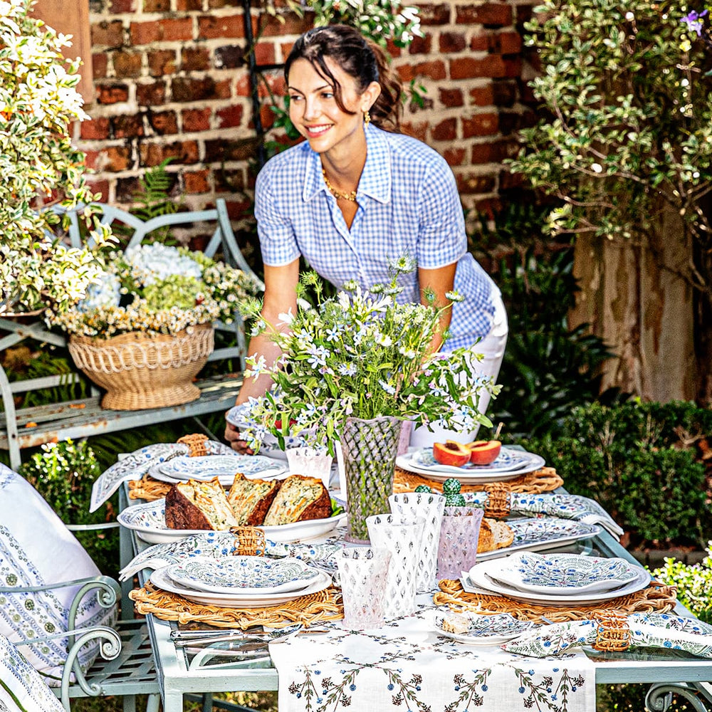 Woman setting down serving bowl on a outdoor floral table setting