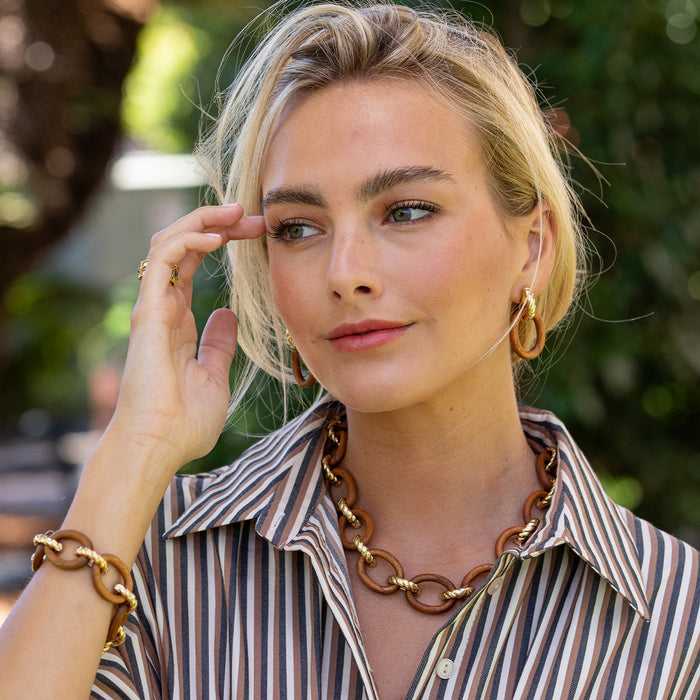 Woman wearing gold jewelry outdoors with a blurred background