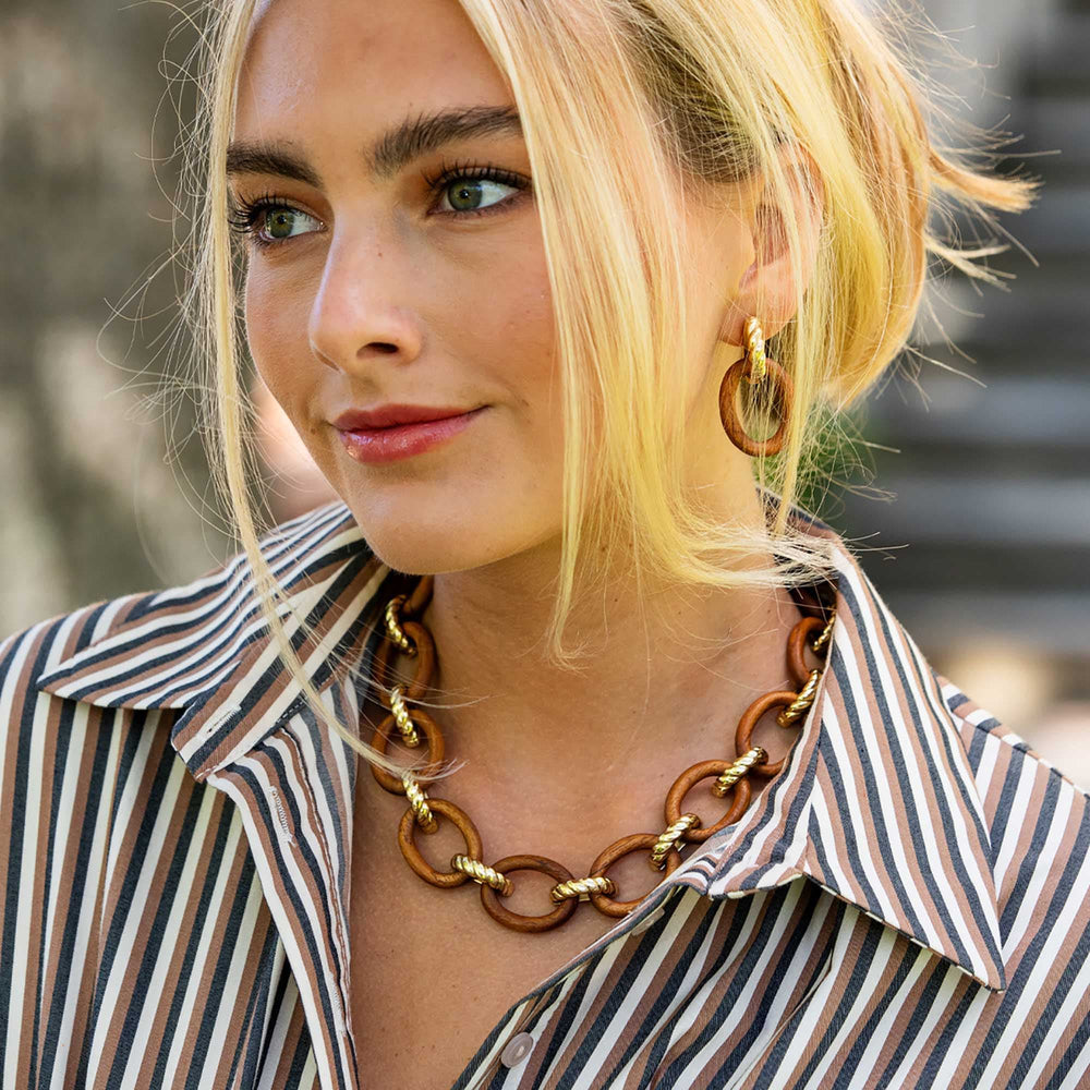 Woman in stripped button down wearing teak necklace and earrings