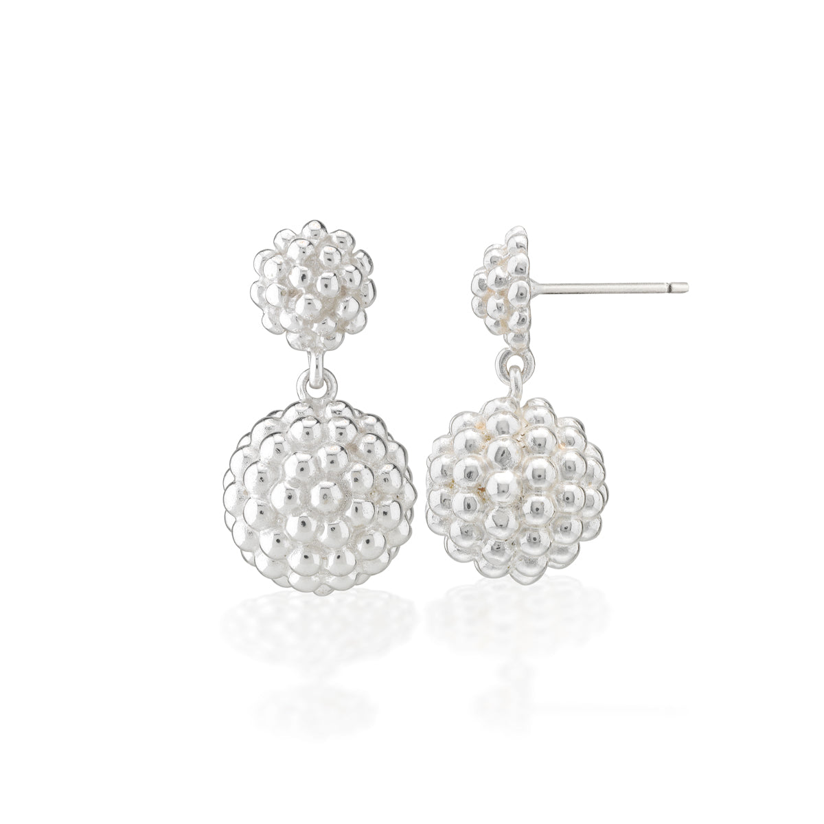 A pair of silver dangle earrings with textured, beaded spherical drops and matching flower-shaped studs, shown on a clean white background with a soft reflection.