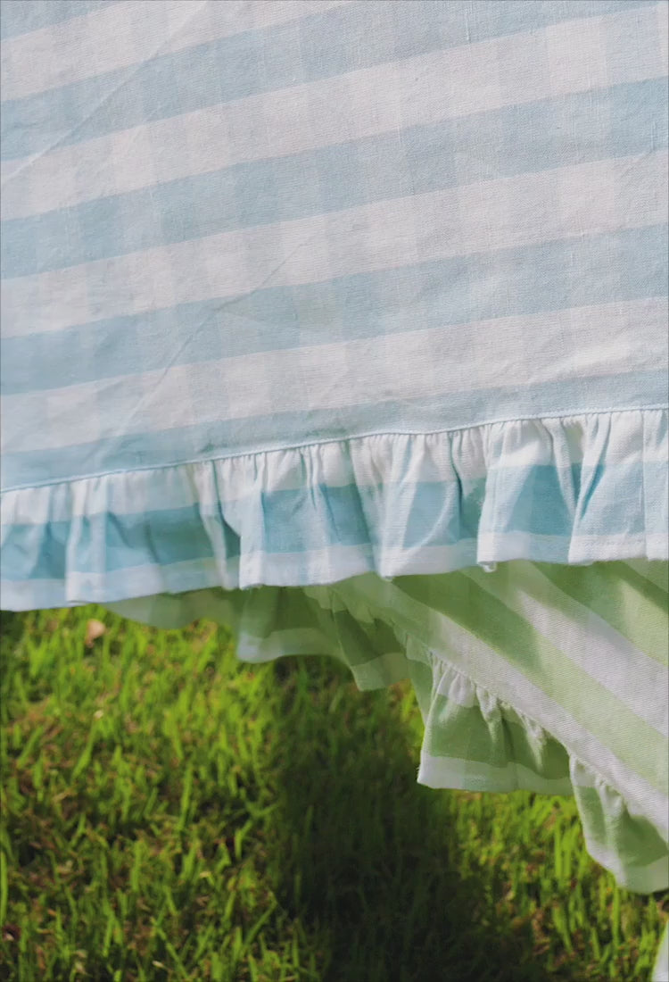 Video of outdoor tablescape featuring blue plates, gingham tablecloth and metal flower candelabras.