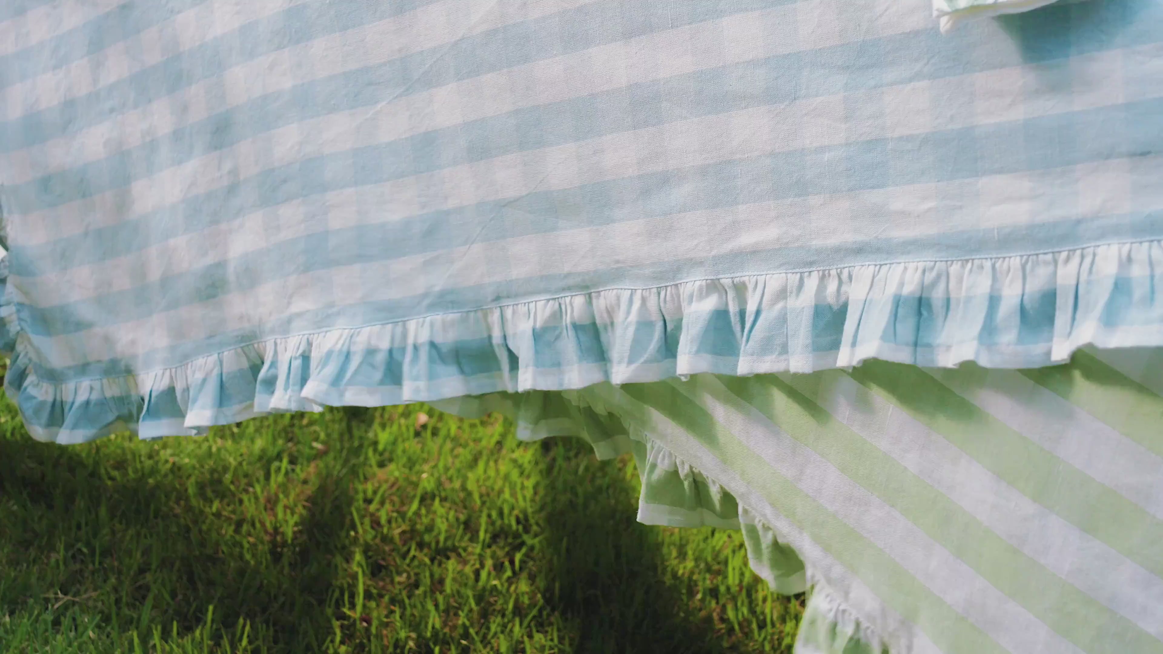 Load video: Video of outdoor tablescape featuring blue plates, gingham tablecloth and metal flower candelabras.
