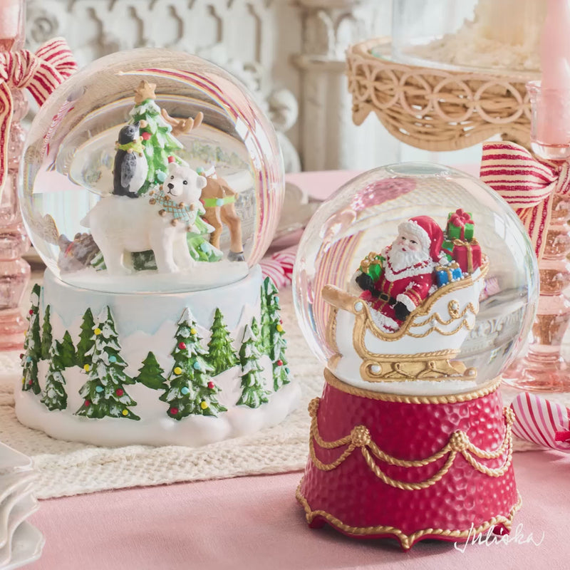 Load video: Video featuring the Juliska "Sugar Plum North Pole" story. The video features a beautifully styled pastel pink holiday table setting featuring white plates, pink and white striped ribbons, penguin figurines, a snow globe, and a tower of macarons in the background.
