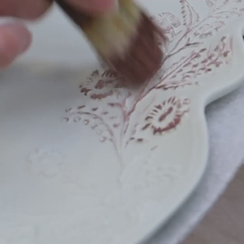 Load video: Video showing the Juliska Eat, Drink &amp; Be Berry story. The video features an elegant table setting featuring ornate gold floral candlesticks with lit taper candles, matching gold and white plates, clear glass goblets, and white napkins on a textured white tablecloth.