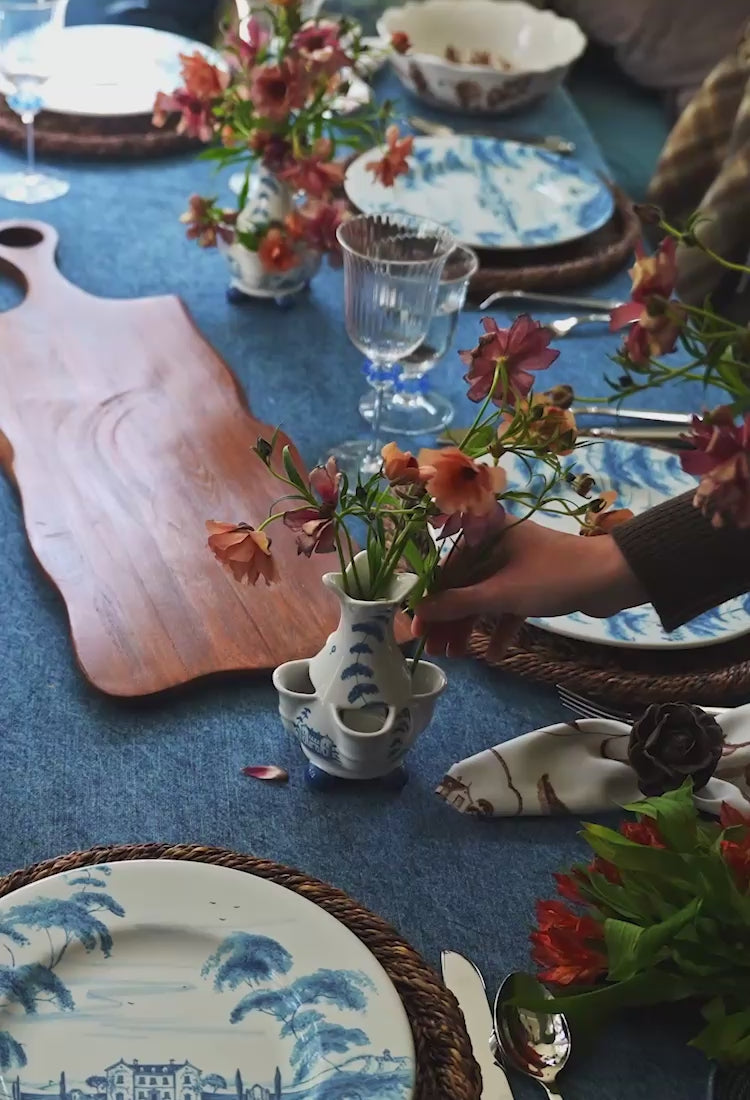 Load video: Video of a layered table setting featuring classic blue and white patterns, rich denim hues, handcrafted ceramics, and natural textures in a relaxed, refined setting.