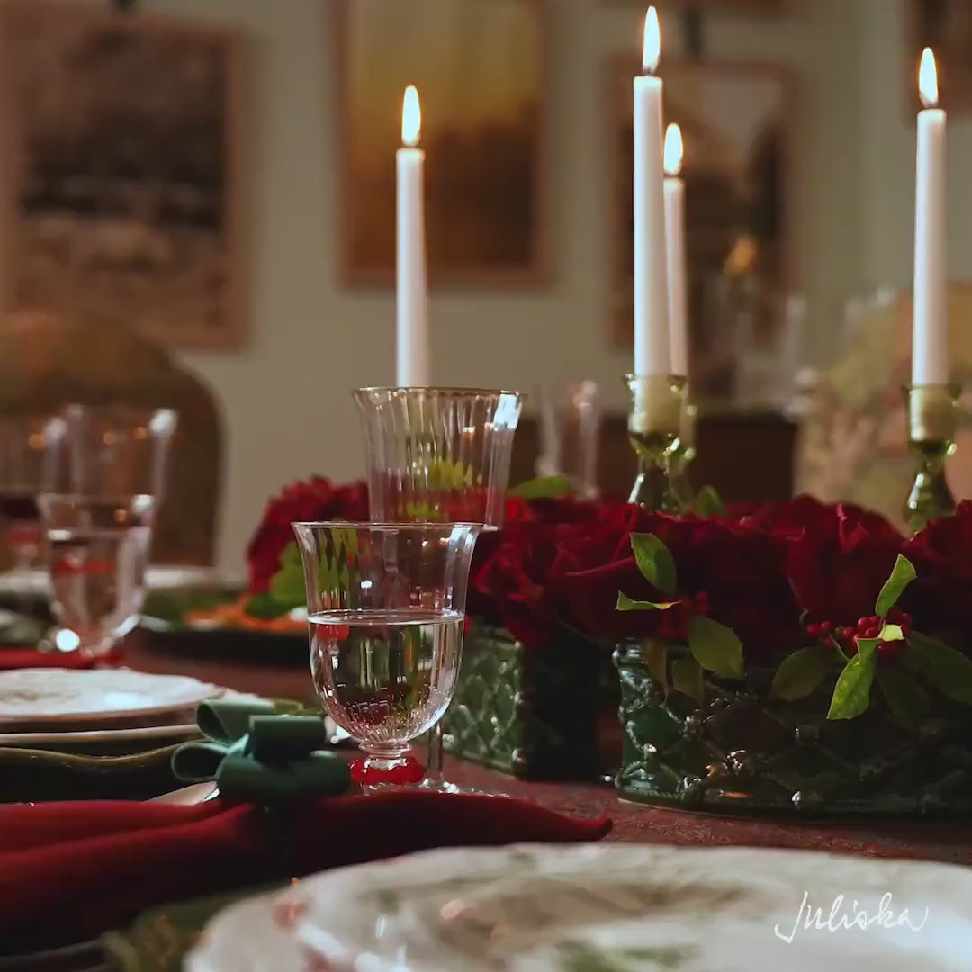 Load video: Video featuring Juliska "Merriment &amp; Magic" story. The video features a festive holiday table setting featuring green and white patterned plates, red napkins, green napkin rings, and a red paisley tablecloth decorated with red roses and white candles.