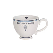 Greet every sunrise with this copious “cofftea cup” that is trimmed in chic black and blue details and is abundantly sized to fuel your daily adventures with coffee, tea, or a decadent chocolat chaud. A petite heart flies alongside our hand sketched Cafe de L’Amour banner and hot air balloon, reminding us to share love wherever the day may take us. 